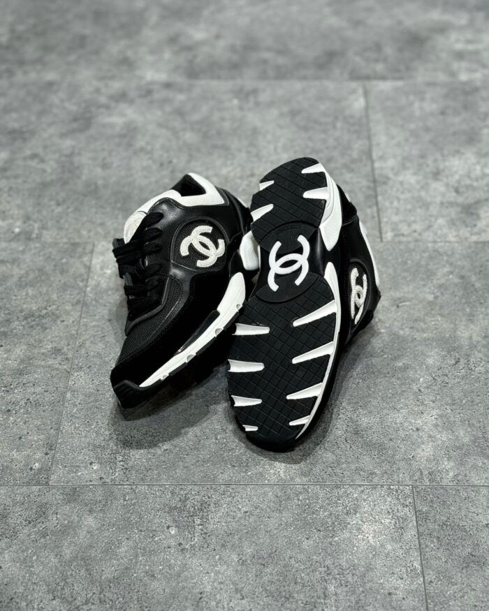 Sneakers Chanel nere e bianche di lusso con logo interlock, stile sportivo e sofisticato.