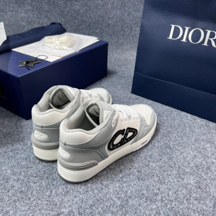 Sneaker Dior di lusso bianca e grigia con borsa navy e branding elegante, stile esclusivo.