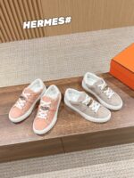 Sneakers Hermès rosa e beige su tavolo in legno, elegante e di lusso con logo iconico.