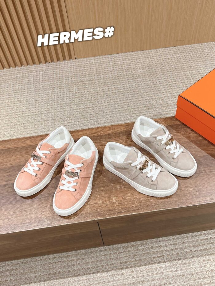 Sneakers Hermès rosa e beige su tavolo in legno, elegante e di lusso con logo iconico.