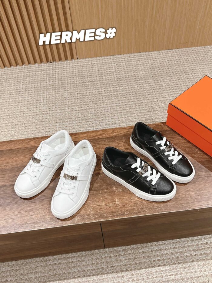 Sneakers di lusso Hermes bianche e nere su sfondo elegante in legno.