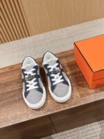 Sneakers moderne grigie con scatola arancione di lusso, stile casual ed eleganza contemporanea.