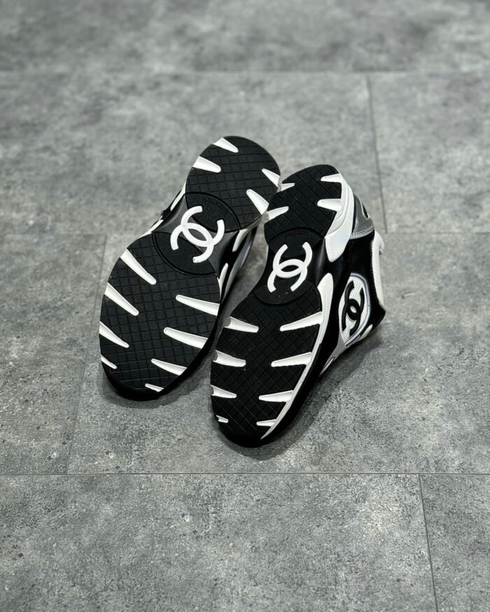 Sneakers di lusso nero e bianco con design moderno, su sfondo grigio neutro.