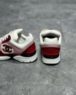 Sneakers di lusso bianco e rosso con logo iconico, dettagli in rosa e design moderno elegante.