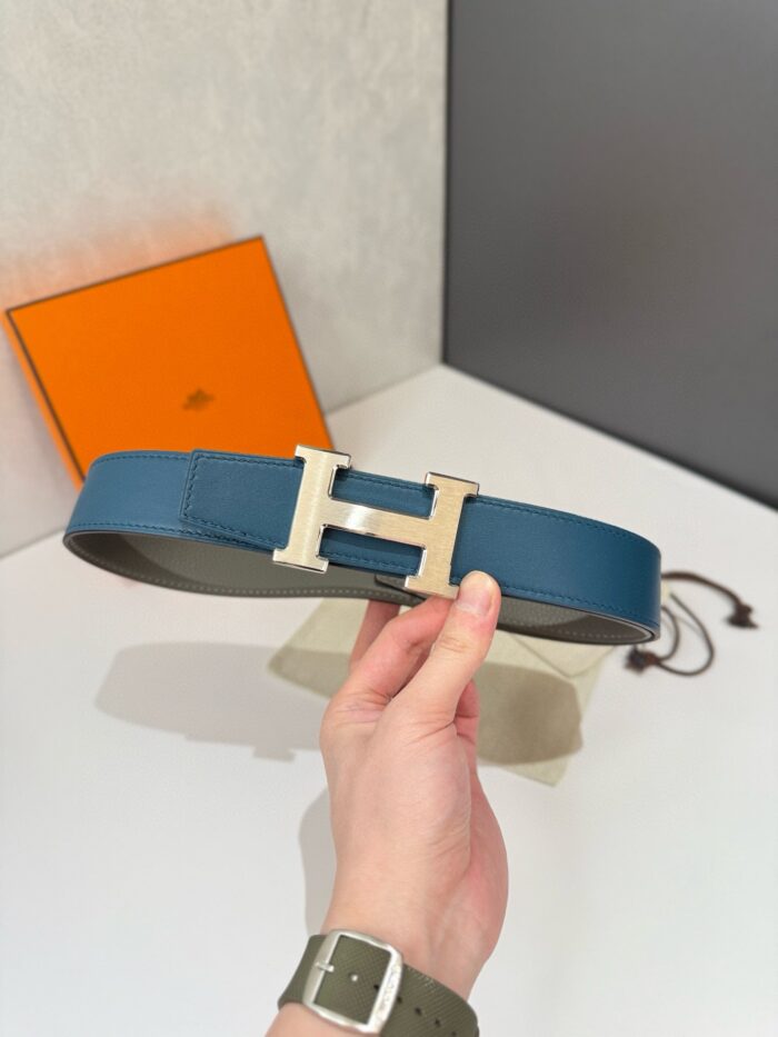 Cintura di lusso blu con fibbia a H in metallo lucido, elegante e moderna.