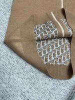 Tessuto marrone di lusso con logo stilizzato e dettagli eleganti, ideale per moda fashion.