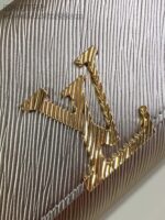 Logo di alta moda in oro su superficie argento con texture elegante e dettagli raffinati.