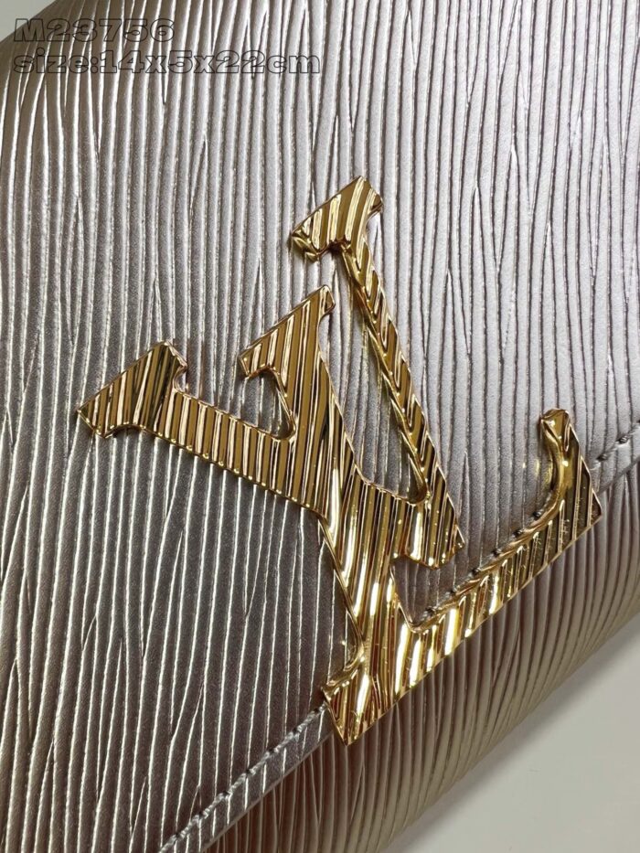 Logo di alta moda in oro su superficie argento con texture elegante e dettagli raffinati.
