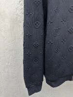 Manica di pullover nero con motivo embossato elegante e dettagli di moda di alta qualità.