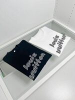 T-shirt di lusso bianca e nera con design artistico, esposta su superficie di vetro raffinata.