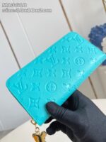 Portafoglio di lusso turchese con charm farfalla e loghi embossed, elegante e di alta qualità.