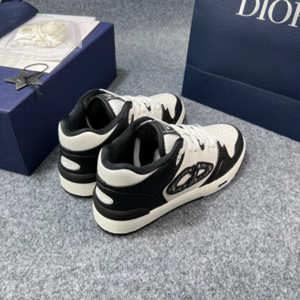Sneakers di lusso bianche e nere con packaging blu elegante e dettagli raffinati.