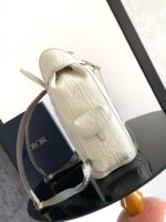 Borsa di lusso bianca in pelle con logo embossato, tracolla iridescente e design elegante.