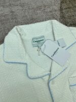 Maglia da pigiama bianca con motivo e piping blu, comfort elegante e stile rilassato.