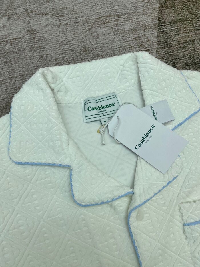 Maglia da pigiama bianca con motivo e piping blu, comfort elegante e stile rilassato.