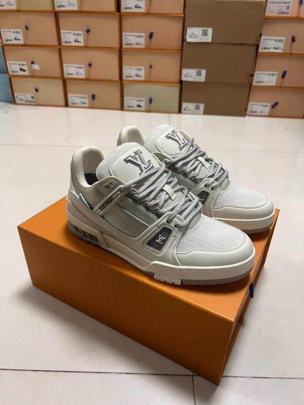 Sneakers bianche di lusso su scatola arancione, design elegante e materiali di alta qualità.
