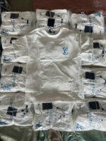 T-shirt bianca Louis Vuitton con logo, esposizione di alta moda e lusso raffinato.