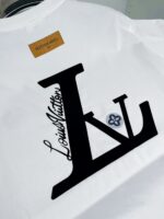 T-shirt bianca Louis Vuitton con logo stilizzato, fiore decorativo e dettagli di lusso.