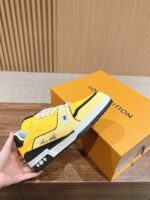 Sneaker gialla di lusso con dettagli neri e bianchi, in mano su scatola arancione elegante.