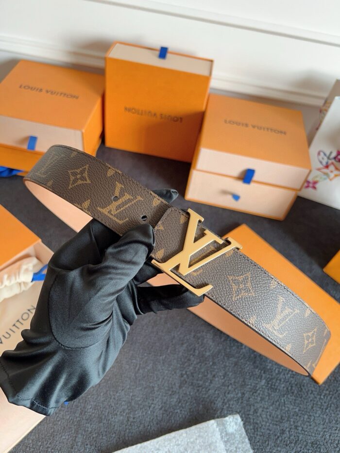 Cintura Louis Vuitton con logo oro, elegante confezione arancione, accessorio di lusso di alta moda.