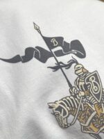 Emblema medievale con cavaliere in armatura e bandiera nera in movimento sulla stoffa.