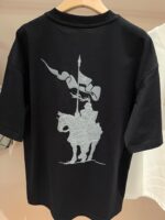 Maglietta nera con cavaliere medievale in sella, grafica dettagliata e stile evocativo.