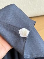Polsino in cotone grigio con etichetta branding, dettaglio di sartoria elegante e qualità.