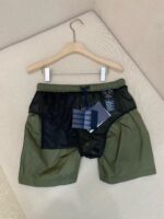 Pantaloncini sportivi verdi oliva con mesh, elastico in vita e cordino blu, perfetti per attività outdoor.