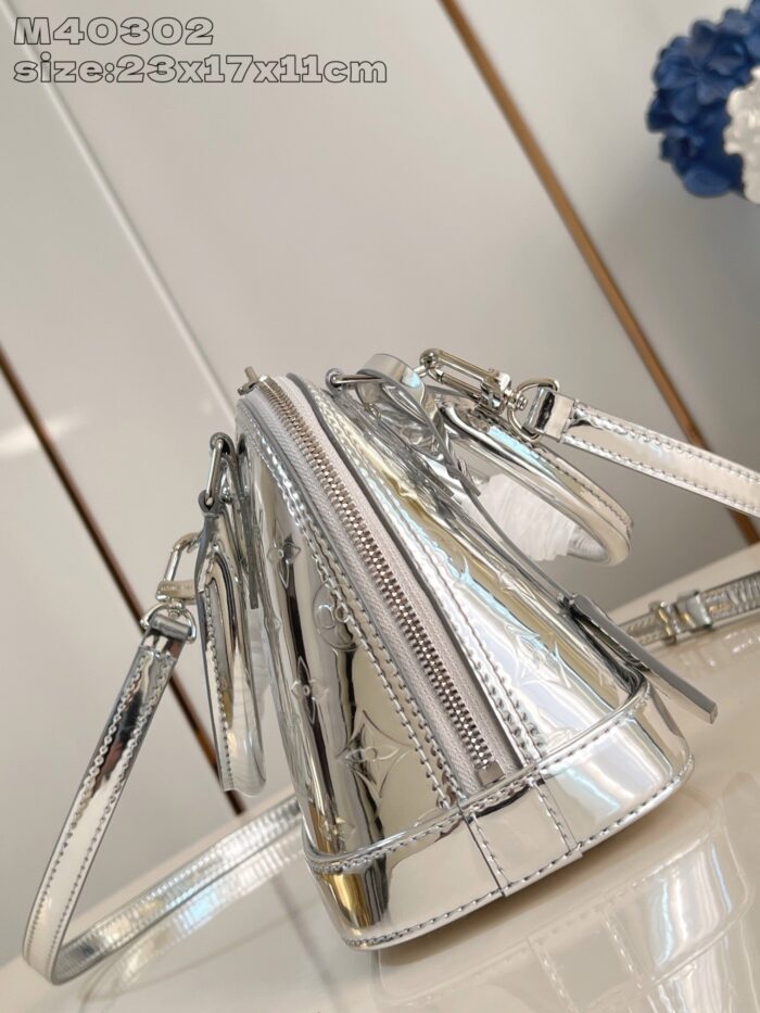 Borsa moderna in argento con forma triangolare, riflettente e dettagli metallici eleganti.
