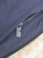 Chiusura lampo elegante su tessuto navy e beige, dettagli di qualità e stile minimalista.