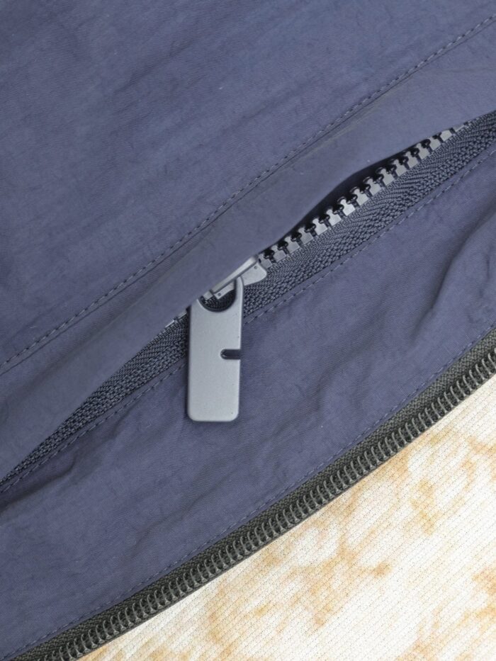 Chiusura lampo elegante su tessuto navy e beige, dettagli di qualità e stile minimalista.