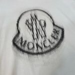 Maglietta con logo circolare stilizzato nero MONCLO e effetto movimento moderno.