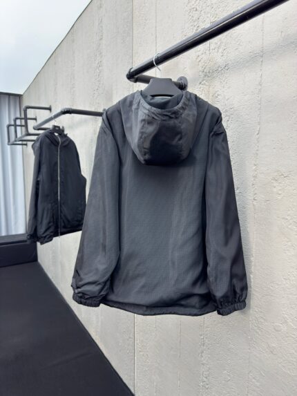 Giacca nera moderna e minimalista su asta in un ambiente elegante e contemporaneo.