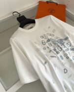 T-shirt bianca con grafica geometrica e borsa arancione in stile minimalista.