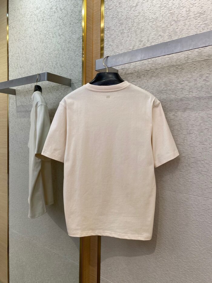 Maglietta beige minimalista su appendiabiti elegante in ambiente moderno e riflettente.