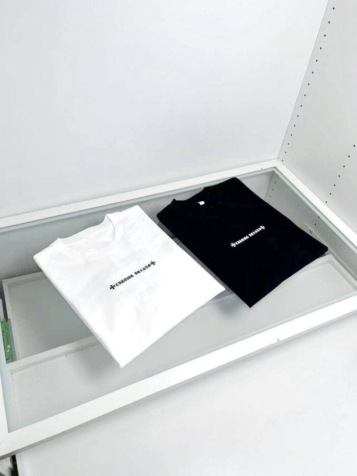 T-shirt minimaliste bianca e nera in esposizione elegante su superficie bianca.
