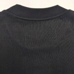 Maglietta nera minimalista con collo a coste e dettaglio rettangolare senza logo.