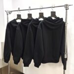 Esposizione moderna di felpe nere opache su supporto in metallo bianco.