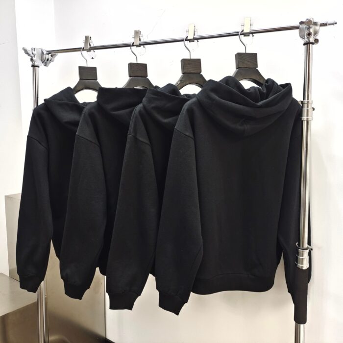 Esposizione moderna di felpe nere opache su supporto in metallo bianco.
