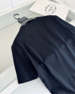 Maglietta nera casual e moderna su sfondo minimalista con logo elegante.