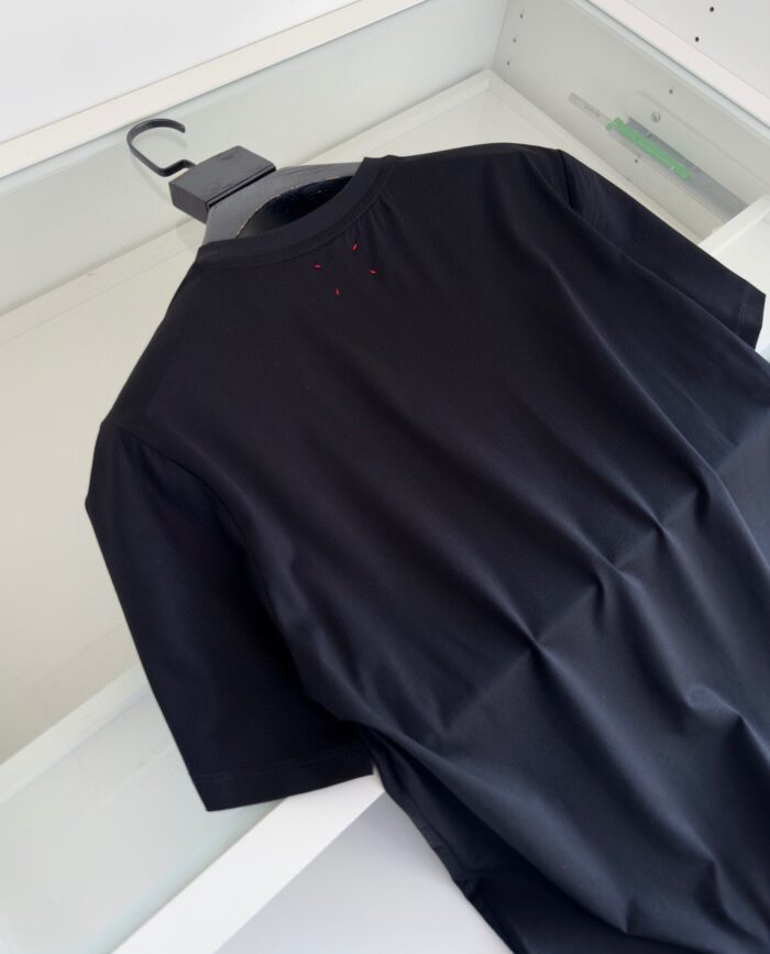 Maglietta nera minimalista in cotone, stile casual e moderno, senza logo e con scollo rotondo.