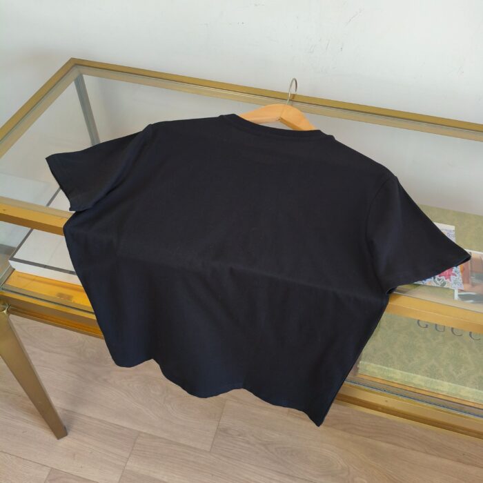 Maglietta nera casual, semplice e versatile su tavolo di vetro e legno, stile minimalista.