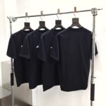 Esposizione di T-shirt nere minimaliste su scaffale moderno in metallo, stile contemporaneo.