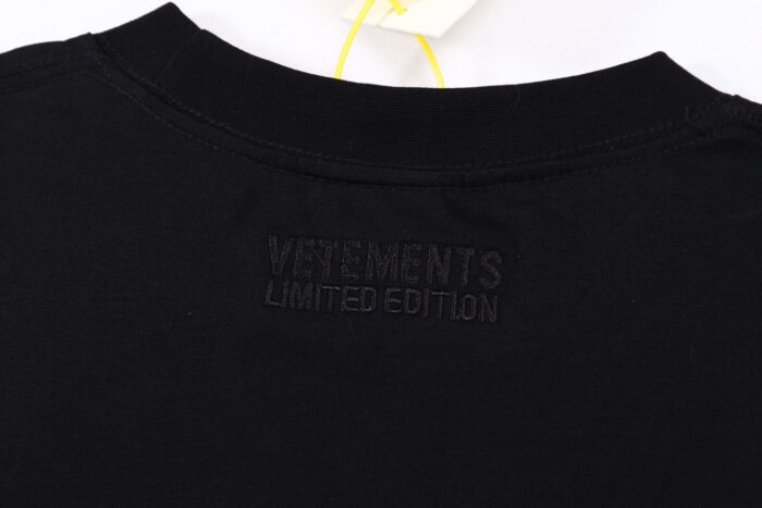 Maglietta nera VETEMENTS Limited Edition con logo embossato e etichetta gialla elegante.
