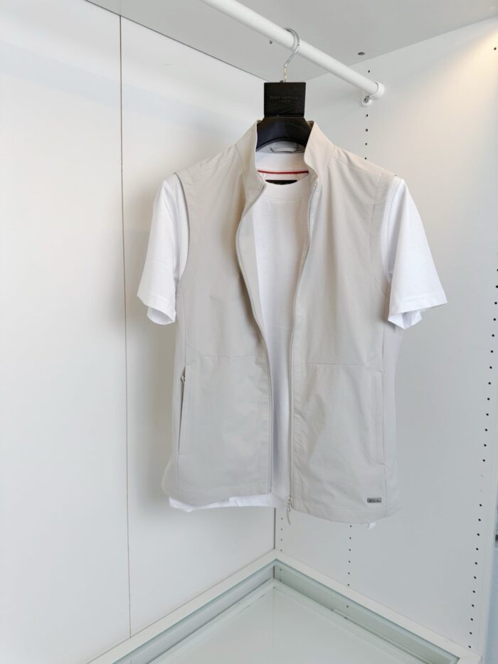 Look elegante e minimalista con gilet grigio e t-shirt bianca su appendiabiti bianco.