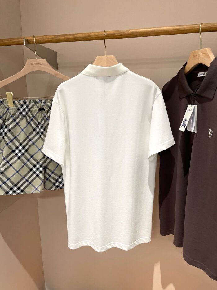 Esposizione minimalista di polo bianche, marroni e pantaloncini check beige su sfondo neutro.