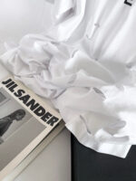 Camicetta bianca volutamente stropicciata su rivista Jil Sander in stile minimalista.