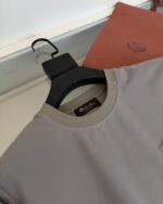 Camicia grigia elegante con dettaglio sul colletto e organizer in cuoio moderno.