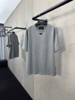 Maglietta grigia minimalista su esposizione moderna con parete ruvida, stile casual elegante.
