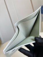 Portafoglio verde menta minimalista con inserti in pelle e manico nero elegante.